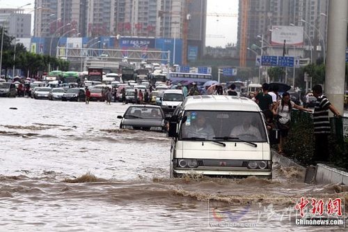 6月18日，车辆在武汉积水的道路上艰难行驶。当日，武汉降大到暴雨，全城多处交通要道积水严重，交通几近瘫痪。中新社发 张畅 摄